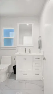 a bathroom with a sink vanity granite toilet and a mirror