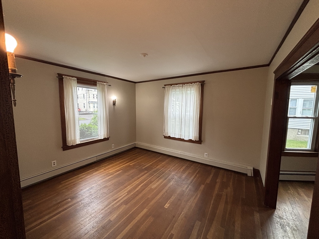 49 Clark Street, Unit 1 Framingham, MA 01702 - Photo 2 of 7 an empty room with wooden floor and windows
