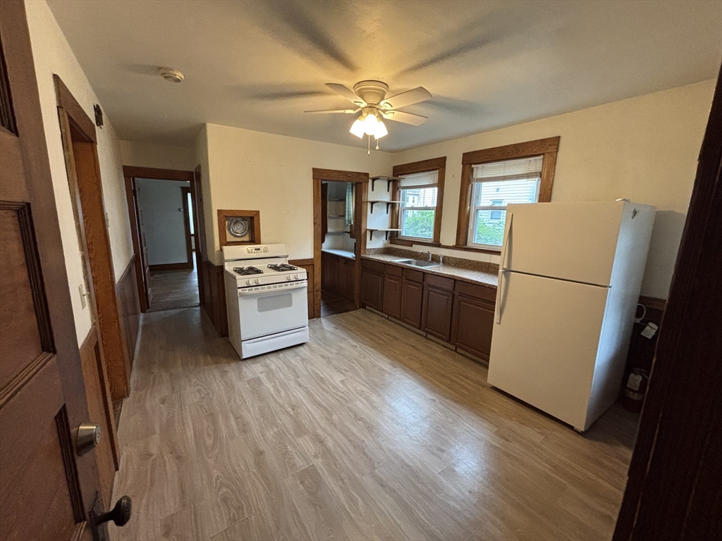 49 Clark Street, Unit 1 Framingham, MA 01702 - Photo 3 of 7 a kitchen with stainless steel appliances granite countertop a refrigerator a stove a sink a washer dryer and white cabinets