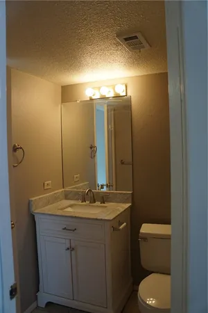 a bathroom with a granite countertop sink toilet and mirror