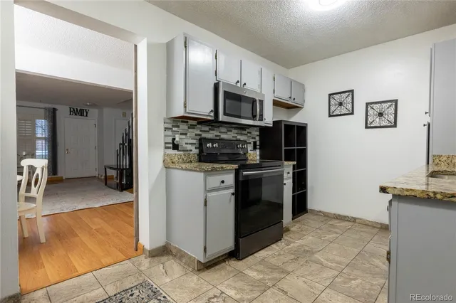 a kitchen with stainless steel appliances granite countertop a stove top oven a sink and a refrigerator