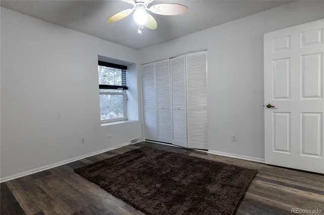 an empty room with wooden floor cabinet and windows