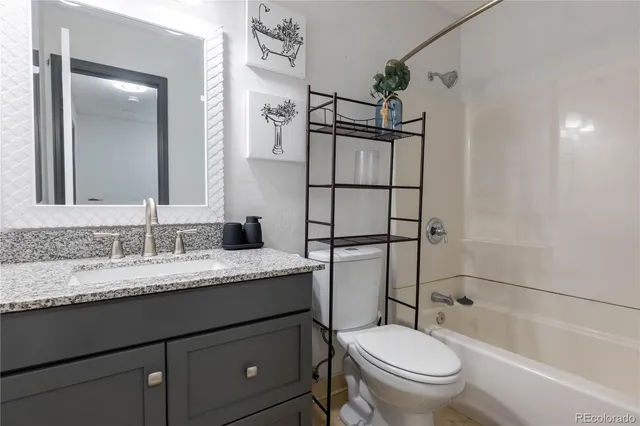 a bathroom with a granite countertop sink toilet mirror and shower