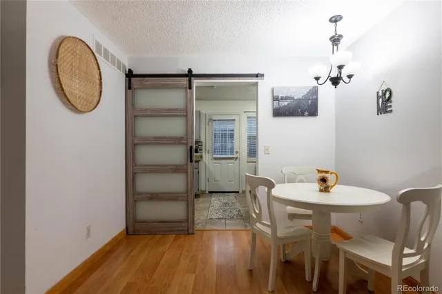 a dining room with wooden floor a glass table and chairs