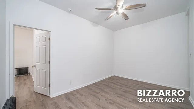 an empty room with wooden floor chandelier fan and windows