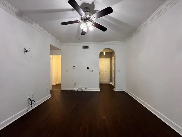an empty room with wooden floor chandelier fan and windows