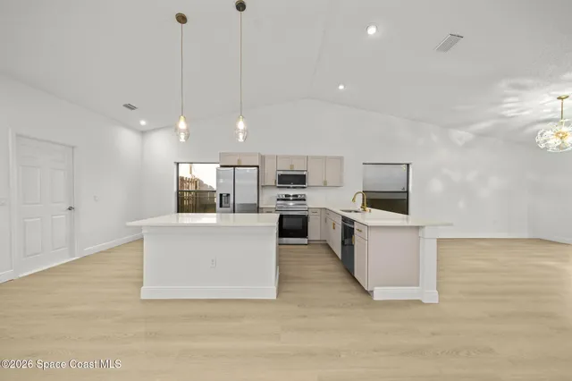 a view of kitchen with microwave a refrigerator and a living room view