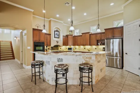 a kitchen with stainless steel appliances kitchen island granite countertop a refrigerator a stove a sink and a chairs