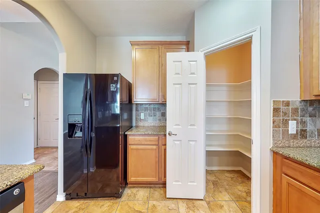 a view of kitchen with granite countertop cabinets and refrigerator