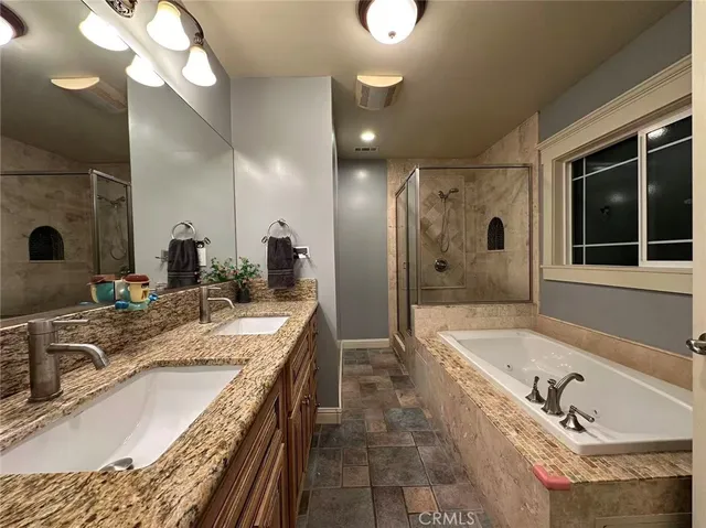 a bathroom with a granite countertop tub a double vanity sink a mirror and shower