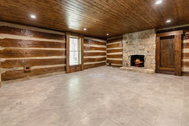 an empty room with wooden floor chandelier fan and windows