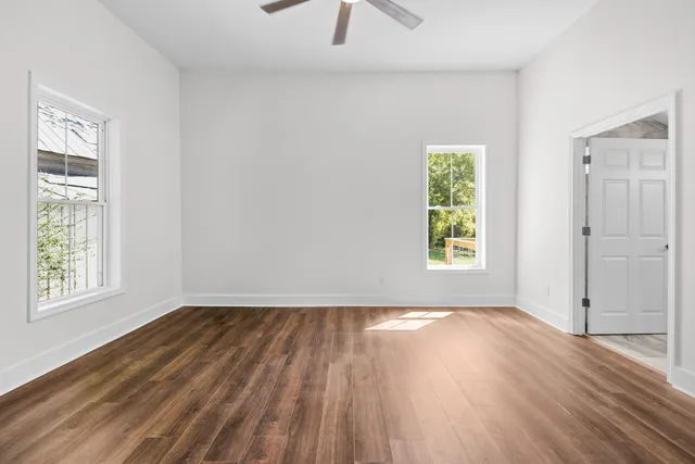 a view of empty room with wooden floor and fan