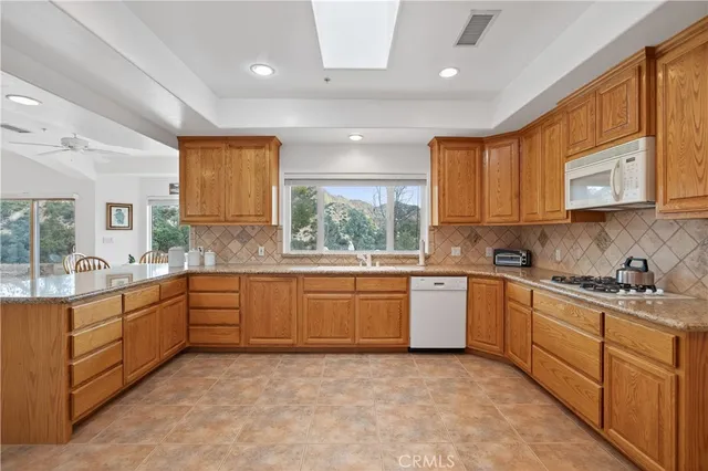 a kitchen with granite countertop a sink a stove and a refrigerator