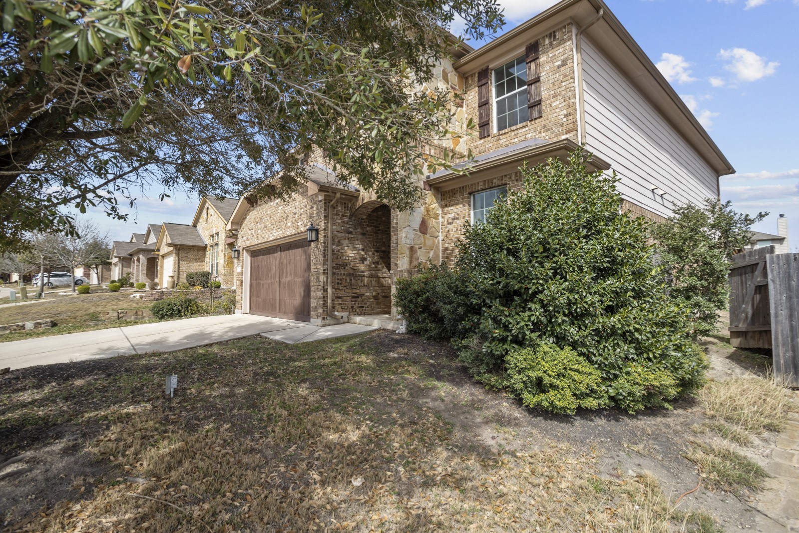 245 Razzmatazz Trail Buda, TX 78610 - Photo 3 of 37 View of front of home with stone siding, concrete driveway, brick siding, and a residential view