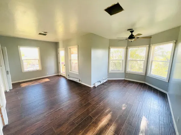 a view of an empty room with wooden floor and a window