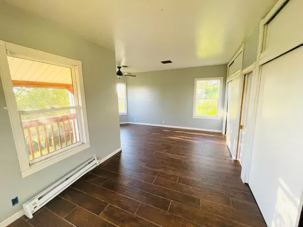 a view of an empty room with wooden floor and a window