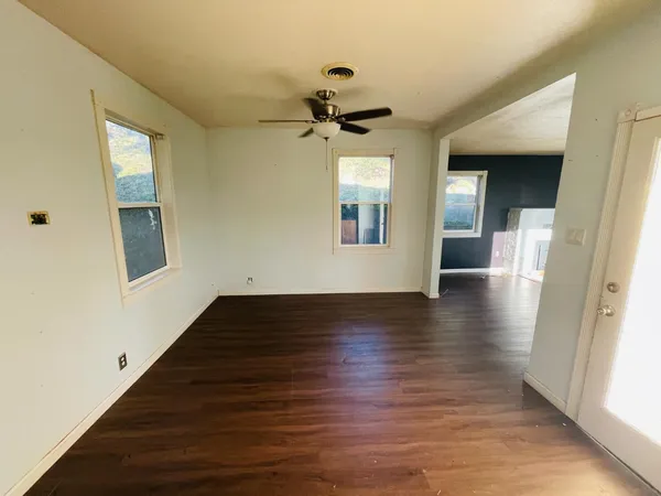 a view of an empty room with wooden floor and a window