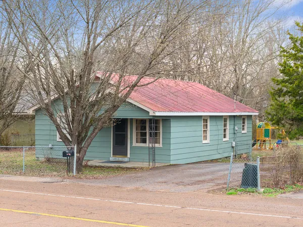 a front view of a house with a garden and trees
