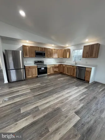 an empty room with wooden floor a ceiling fan and windows
