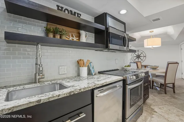 a kitchen with granite countertop stainless steel appliances a sink and a stove