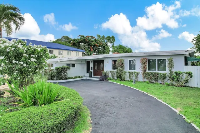 a view of a house with a big yard plants and large trees