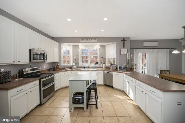 a large white kitchen with cabinets a sink a stove a window and white stainless steel appliances