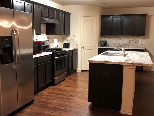a kitchen with kitchen island granite countertop a sink stove and refrigerator