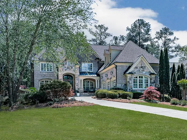 a front view of a house with a garden and trees