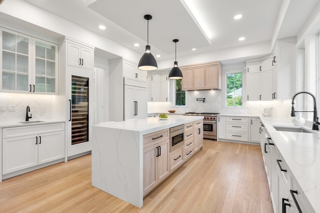 91 Oldham Road Newton, MA 02465 - Photo 7 of 38 a kitchen with stainless steel appliances a stove a sink dishwasher a refrigerator white cabinets and wooden floor next to a window
