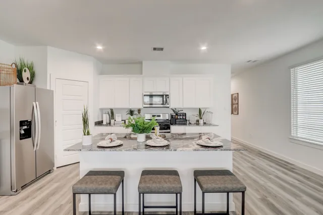 a kitchen with stainless steel appliances granite countertop a dining table chairs and chandelier