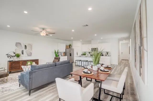 a living room with furniture and a dining table with wooden floor