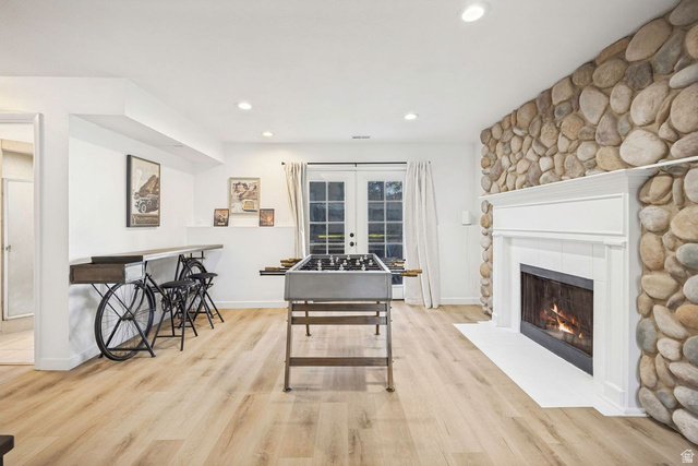 1723 Albury Road Sandy, UT 84092 - Photo 18 of 23 Spacious room featuring a prominent stone fireplace with a white mantel, light wood-finish flooring, recessed lighting, and French doors