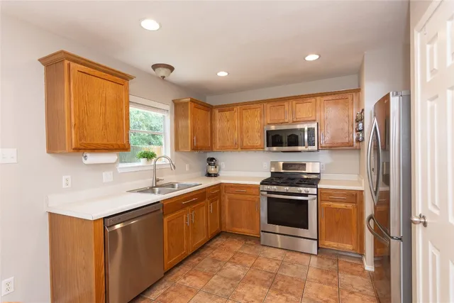a kitchen with stainless steel appliances granite countertop a sink stove refrigerator and cabinets