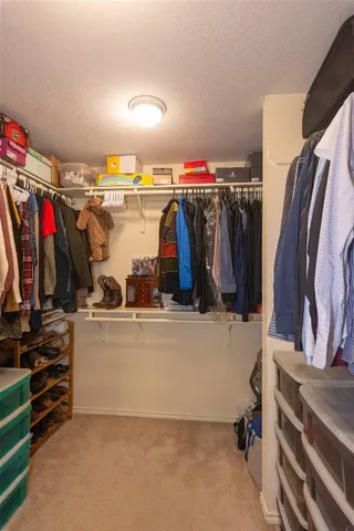 a view of walk in closet with clothes and shoes