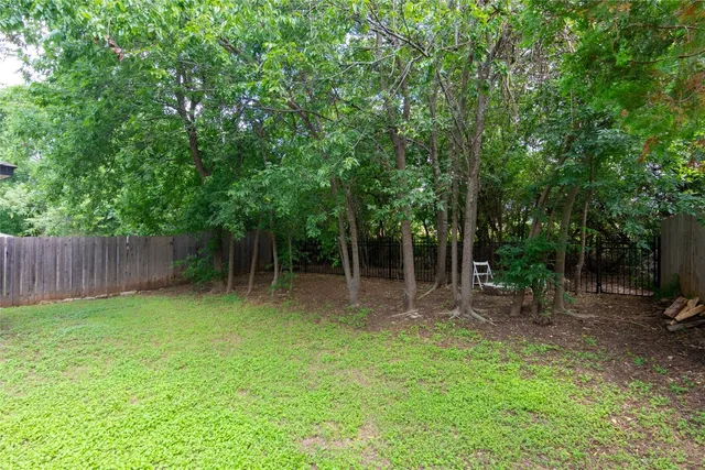 a backyard of a house with lots of plants and large tree