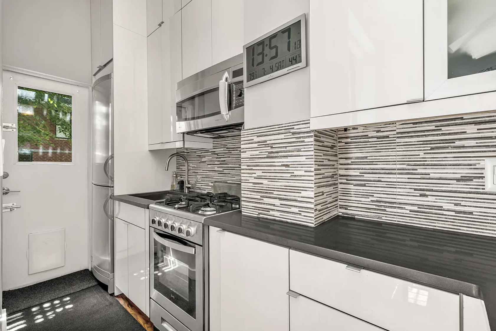 424 East 77th Street, Unit 1D Manhattan, NY 10075 - Photo 5 of 8 a kitchen with stainless steel appliances granite countertop white cabinets and a stove