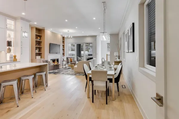 a dining hall with stainless steel appliances a dining table wooden floor and a kitchen view