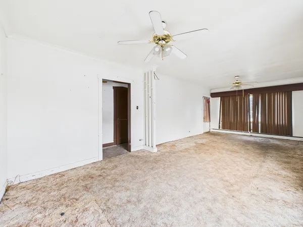 a view of an empty room with a chandelier fan