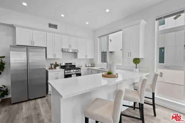 a kitchen with a sink a refrigerator and chairs