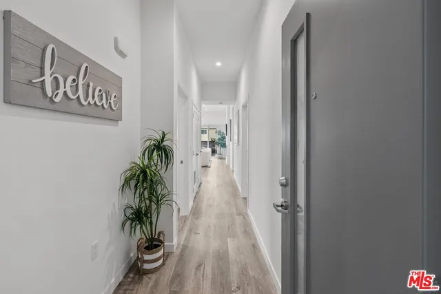 a view of a hallway with wooden floor and a potted plant