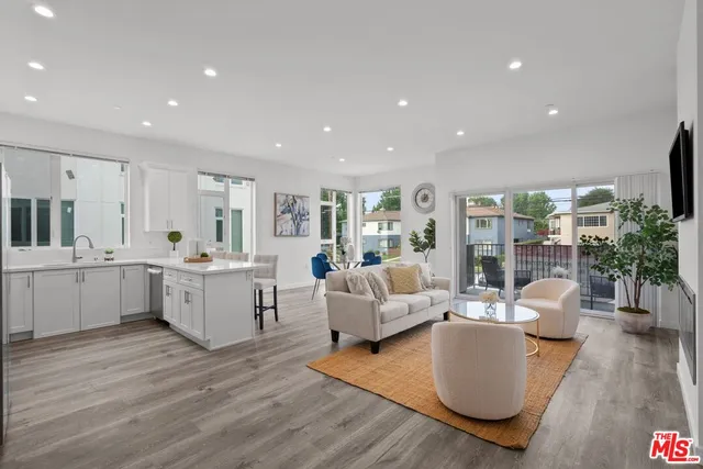 a large living room with stainless steel appliances granite countertop a couch wooden floor and a large window