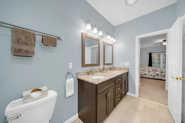 a bathroom with a granite countertop sink a toilet and mirror