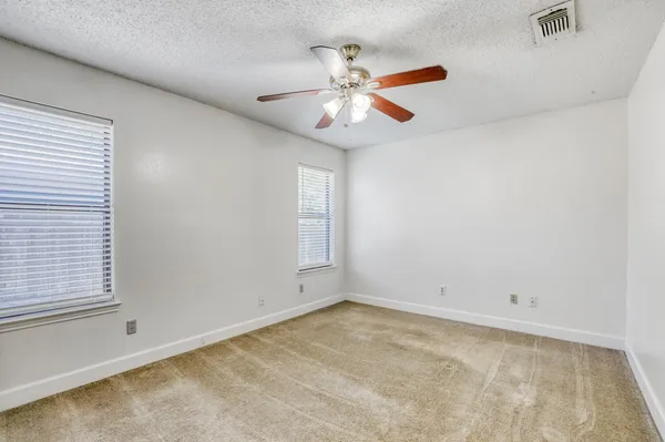 a view of an empty room with chandelier fan and window