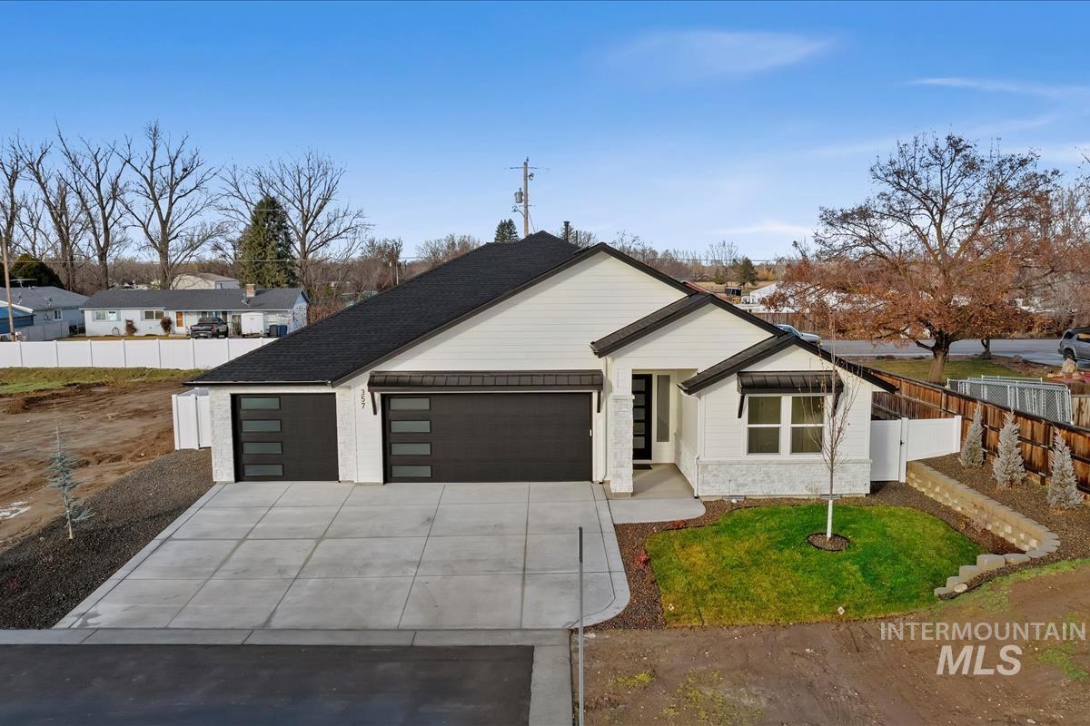 View of front of property featuring a garage, concrete driveway, and stone siding