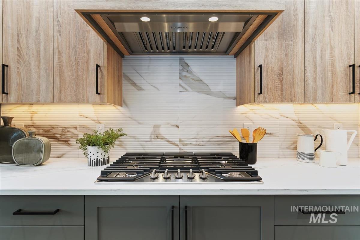 357 West Flour Mill Middleton, ID 83644 - Photo 13 of 49 Kitchen featuring ventilation hood, stainless steel gas cooktop, light stone countertops, gray cabinetry, and backsplash