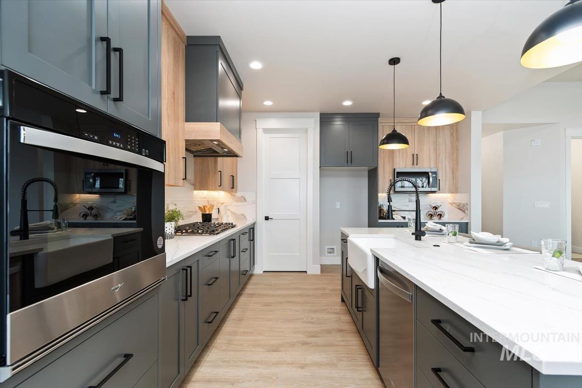 357 West Flour Mill Middleton, ID 83644 - Photo 16 of 49 Kitchen with stainless steel appliances, light stone countertops, light wood-style flooring, two tone cabinets, and decorative light fixtures