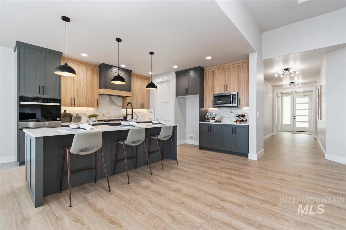 357 West Flour Mill Middleton, ID 83644 - Photo 19 of 49 Kitchen featuring decorative light fixtures, a kitchen breakfast bar, backsplash, oven, and an island with sink