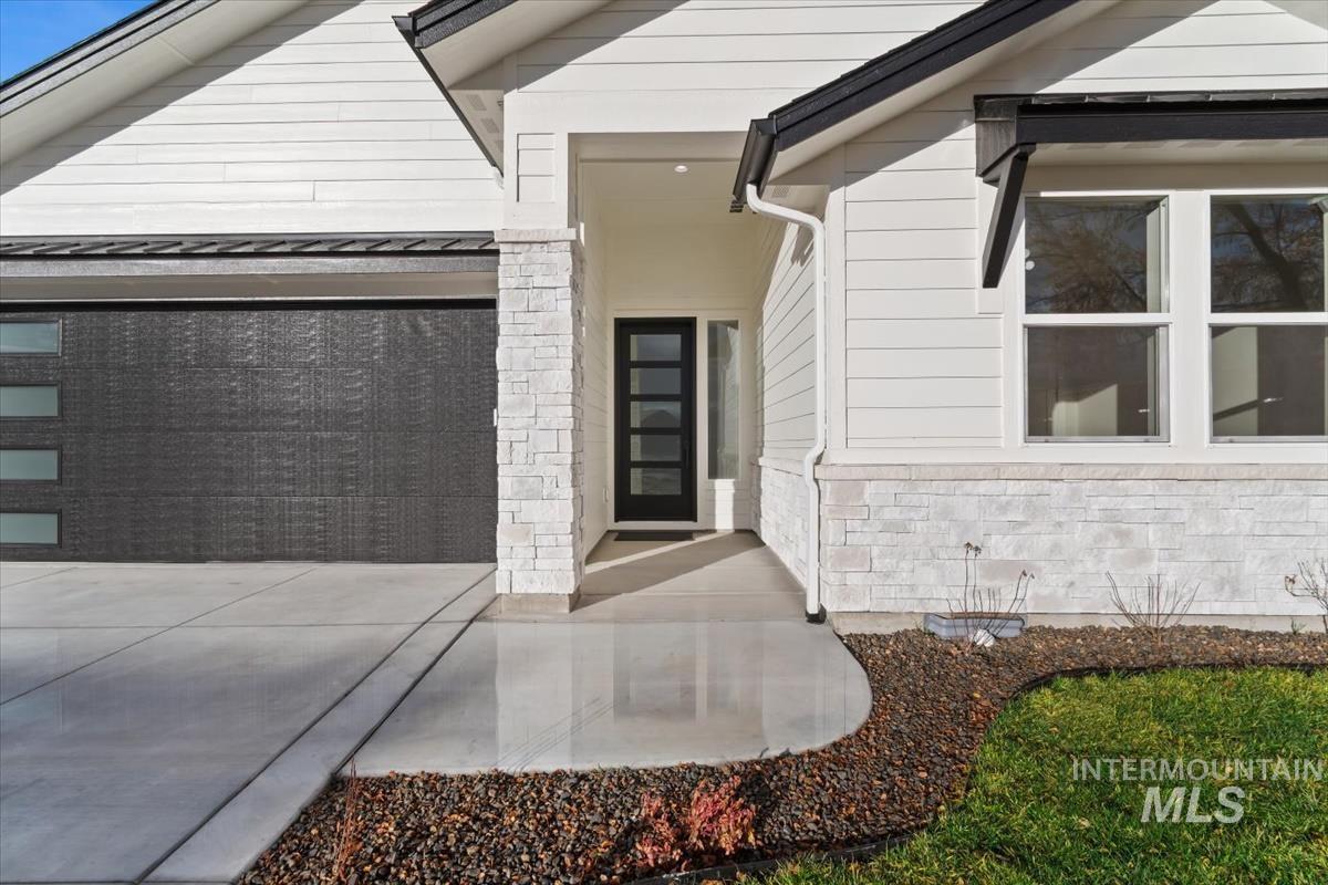 357 West Flour Mill Middleton, ID 83644 - Photo 3 of 49 Property entrance with an attached garage, concrete driveway, stone siding, and a standing seam roof