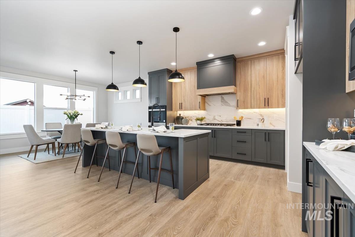 357 West Flour Mill Middleton, ID 83644 - Photo 7 of 49 Kitchen with decorative light fixtures, a breakfast bar, light stone countertops, light wood-type flooring, and an island with sink
