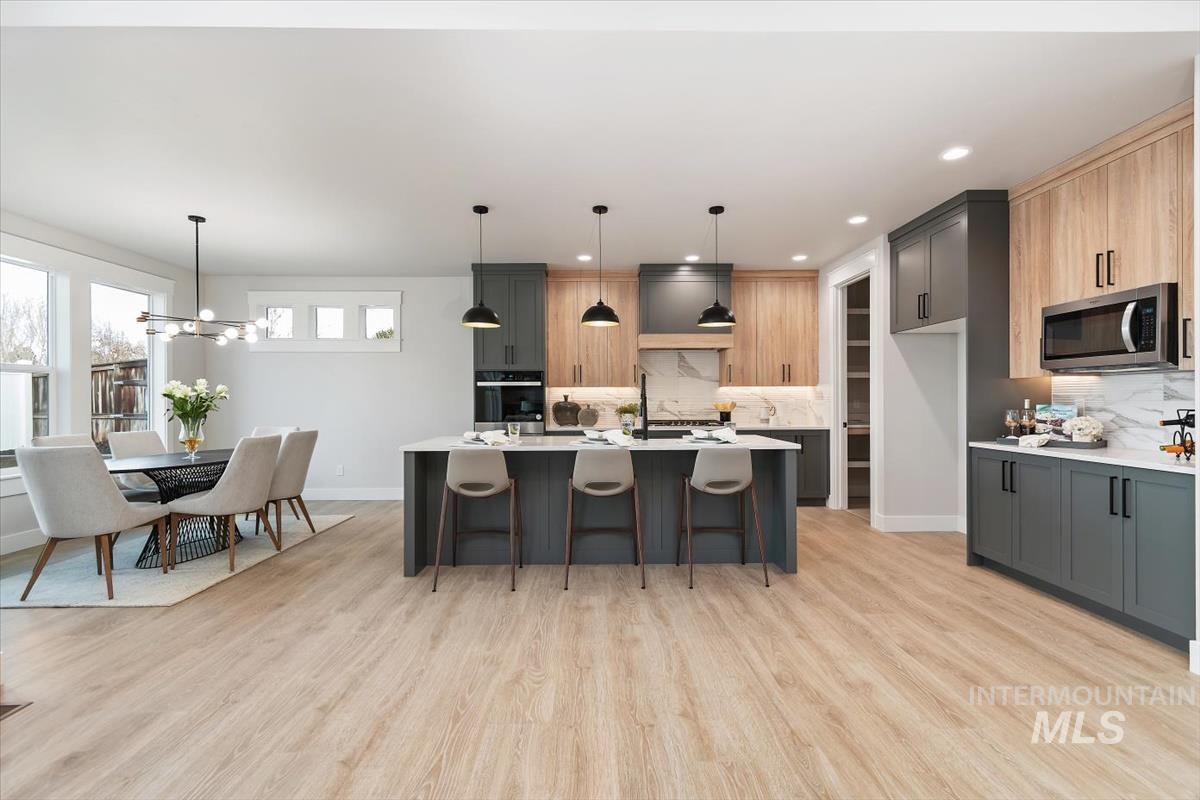 357 West Flour Mill Middleton, ID 83644 - Photo 10 of 49 Kitchen with a kitchen bar, a kitchen island with sink, light stone countertops, stainless steel appliances, and light wood-style flooring